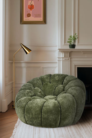 A beautiful green snug armchair in a large victorian room.