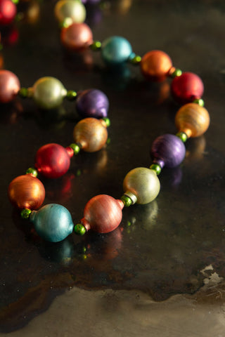 Detail shot of the Multi-Colour Bauble Garland displayed on a dark surface.