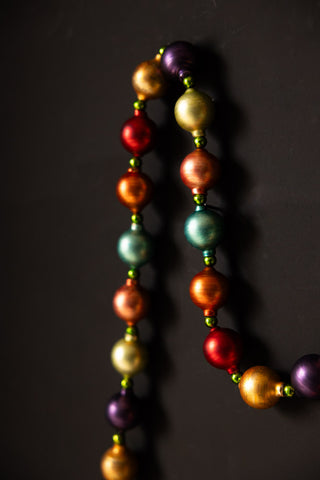 Close-up of the Multi-Colour Bauble Garland draped on a black wall.