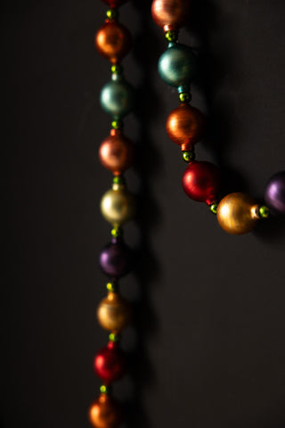 Close-up of the Multi-Colour Bauble Garland hanging in front of a black wall.