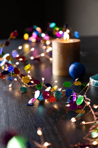 The Multi Coloured Confetti Decorative Light Chain styled on a table amongst candles and decorations.