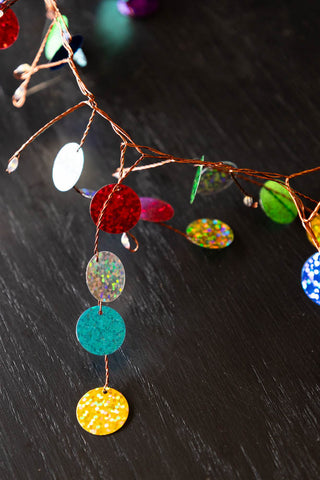 Close-up of the Multi Coloured Confetti Decorative Light Chain displayed on a dark wooden surface.