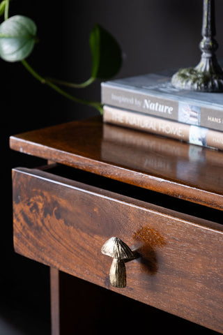 The Mushroom Knob - Gold styled on an open drawer, with books, a candlestick holder and a plant in the background.