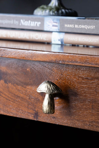 The Mushroom Knob - Gold styled on the drawer of a wooden desk, with books and a candlestick holder styled on top.