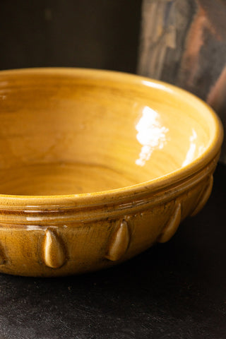 Close-up of the the Mustard Ceramic Serving/Fruit Bowl on a dark wooden surface.