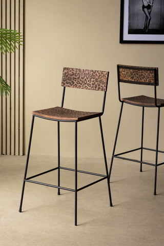 Two of the Natural Leopard Love Bar Stools displayed in a neutral room with an art print and a plant.