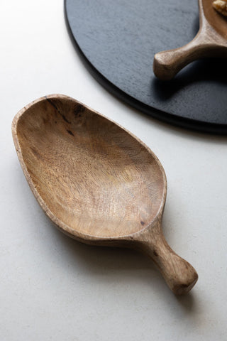 The Natural Wood Carved Serving Dish on a kitchen worktop.
