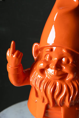 Close-up of orange fibreglass gnome with one finger up in a rude gesture