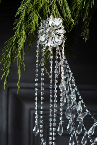 Close-up of the Opulent Crystal Decoration hanging from a fireplace with some greenery.