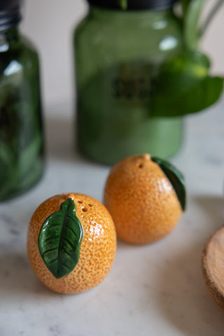 The Orange Salt & Pepper Shakers displayed on a kitchen worktop with other kitchen accessories.