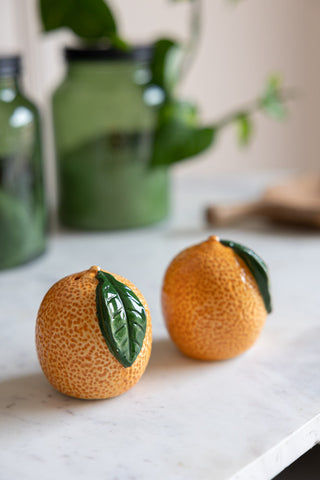 The Orange Salt & Pepper Shakers styled together on a marble worktop.