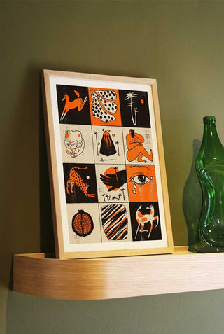 A graphic grid of 12 images in orange, black and white featuring illustrations of cats, women, horses and object. The print is framed in an oak frame on a shelf.