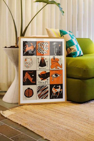 The Orange tones artprint framed lent against a side table and sofa.