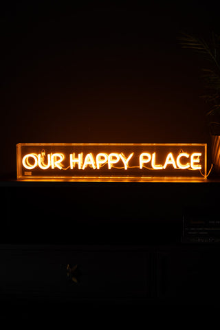 The Our Happy Place Neon Light Box illuminated in the dark.