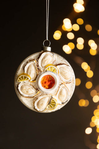 The Oyster Christmas Tree Decoration hanging in front of a dark background with fairy lights.