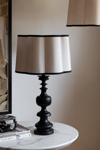 The Oyster Scalloped Easyfit Lampshade styled on a lamp base on a marble table, with some books, a trinket box and a piece of artwork.