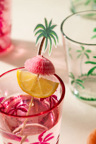 Close-up of one of the Palm Tree Party Toothpicks in a glass, with a slice of lemon on.