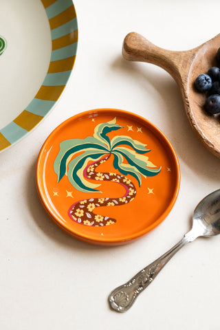 The Palm Tree Small Side Plate styled next to a wooden serving tray and a blue and yellow plate.