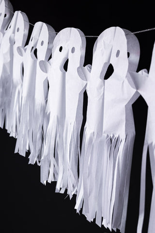 The Paper Ghost Halloween Garland draped in front of a black wall.