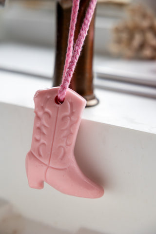 Image of the Pink Cowboy Boot Soap On A Rope styled hanging on a tap over a white sink.