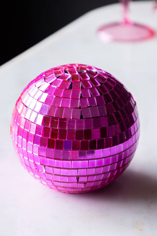 Hot pink disco ball sat on a side table.