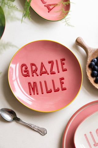 The Pink Grazie Mille Plate styled with other colourful plates, serveware, cutlery, fruit and a plant.