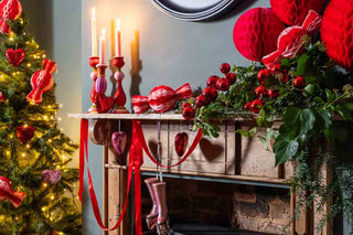 A red fireplace with baubles, garlands and candlesticks.