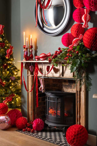 Lifestyle image of the Pink Disco Heart Christmas Tree Decoration styled in a Christmas red and pink living room.