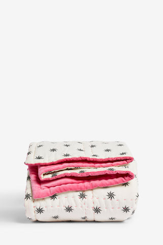 The Reversible Hot Pink Star Throw folded up, in front of a white background.