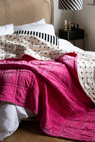 The Reversible Hot Pink Star Throw draped across a bed.