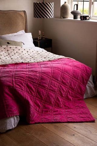 The Reversible Hot Pink Star Throw styled across a bed.