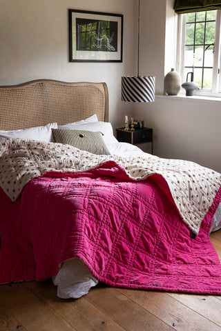 The Reversible Hot Pink Star Throw styled draped across the corner of a bed.