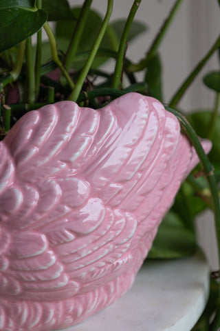 The wing of the pink swan vase. The vase is glazed and you can see the texture of the feather details.