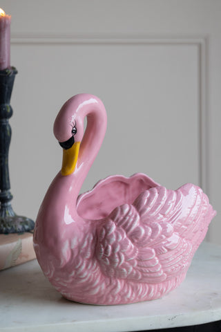 The pink swan planter sat on a sideboard. 