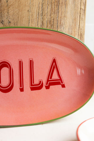 Close-up of the Pink Voila Plate leaning against a wooden chopping board.