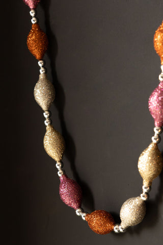 Close-up of the Pink & Gold Sparkle Bauble Garland draped on a black wall.