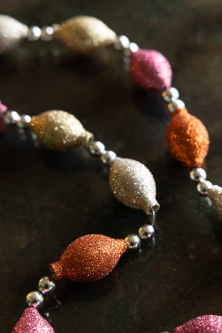 Close-up of the Pink & Gold Sparkle Bauble Garland displayed on a dark surface.