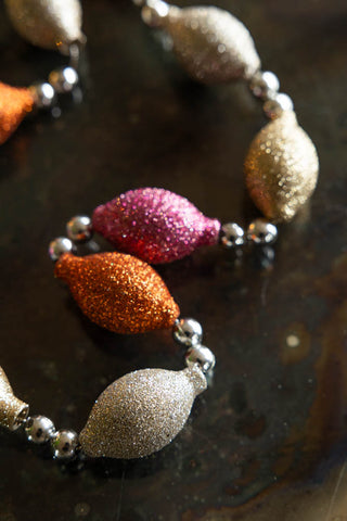 Detail shot of the Pink & Gold Sparkle Bauble Garland displayed on a dark surface.