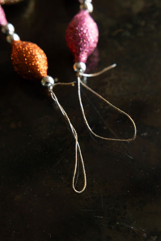 Close-up of the hanging loops on the Pink & Gold Sparkle Bauble Garland, displayed on a dark surface.