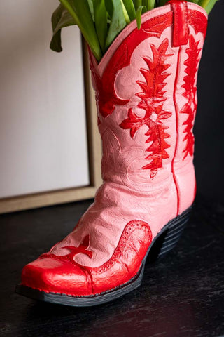 Close-up of the Pink & Red Cowboy Boot Vase on a dark wooden surface.