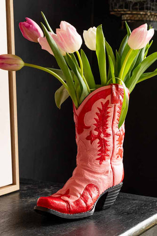 The Pink & Red Cowboy Boot Vase on a black wooden surface, styled with some tulips inside.