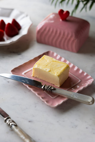 The Pink & Red Heart Butter Dish with the lid off, styled with butter and a knife.