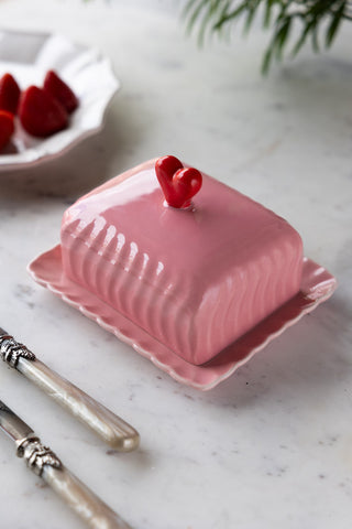 The Pink & Red Heart Butter Dish styled on a table with cutlery and a plate of strawberries.