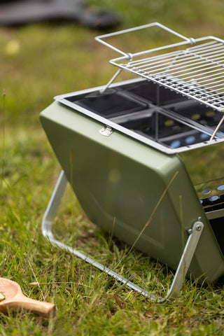Detail shot of the Portable Suitcase BBQ - Khaki Green displayed outdoors on grass.