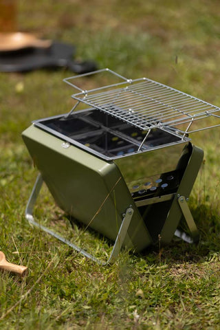 Side view of the Portable Suitcase BBQ - Khaki Green displayed outdoors on grass.