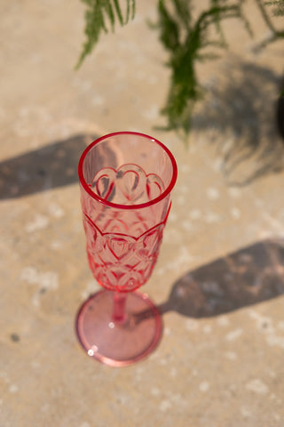 The Pretty Embossed Pink Champagne Glass seen from above, styled on an outdoor table with a plant.