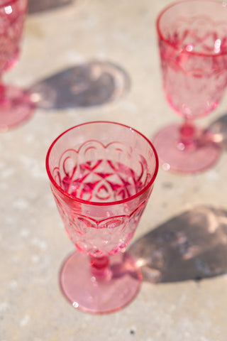 Several Pretty Embossed Pink Wine Glasses styled on an outdoor table.