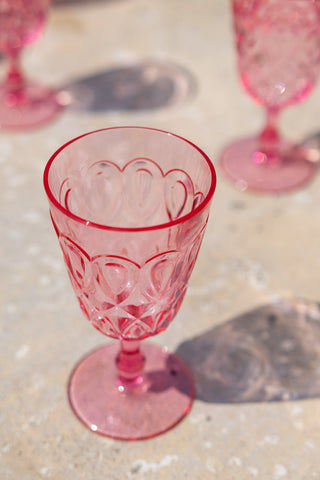 Detail shot of the Pretty Embossed Pink Wine Glass displayed on a table outdoors.