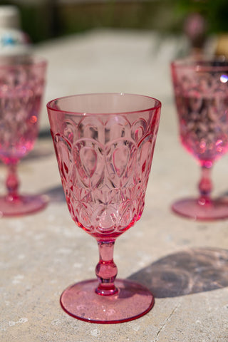 Shot focused on one Pretty Embossed Pink Wine Glass with two others in the background.