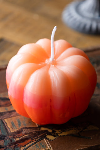 Detail shot of the Pink Ombre Pumpkin Candle on a book.